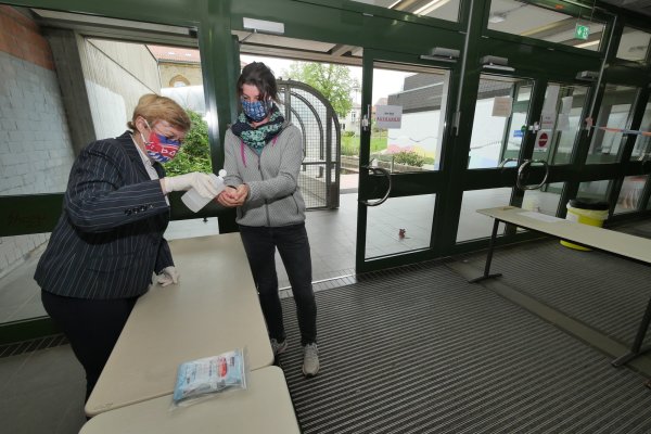 Grabbe-Schulleiterin Daniela Faude und Lehrerin Nadine Schlottmann führen vor, wie sich die Schüler vor den Abiturprüfungen am Gebäudeeingang die Hände desinfizieren können. Die Gittertüren des „Löwengangs" zum Altbau im Hintergrund werden geschlossen bleiben. Am Eingang und in den Treppenhäusern gilt eine Einbahnstraßenregelung. - © Jost Wolf