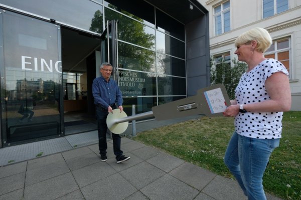 Eine Hygienestation für den Eingang: Mario Rakusa und Simone Nolte tragen sie ins Landesmuseum, wo sie am Eingang stehen soll. Es gibt noch weitere, allerdings wartet das Museum zurzeit noch auf das Mittel zur Befüllung. - © Sven Koch