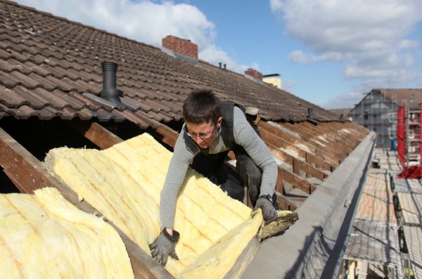Dachdeckerin Anja van Ißem dämmt das Dach eines Hauses mit Mineralwolle – nur ein Baustein, um aus einer Energieschleuder ein Effizienzhaus zu machen. - © picture alliance / dpa