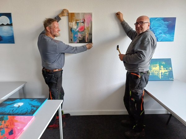 Die Mitarbeiter des Vereins "Arbeit Werkstatt Bildung" Hartmut Strunk (links) und Torsten Filges hängen die Bilder auf. - © awb