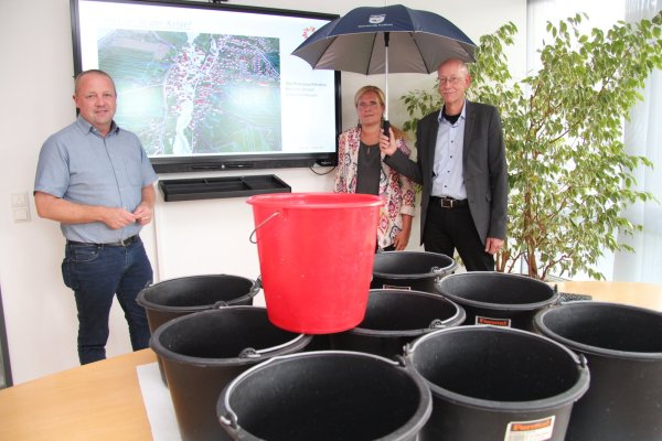 Bürgermeister Mario Hecker (von links), Gemeindemitarbeiterin Corinna Will und Rüdiger Kuhlemann vom Kreis Lippe beim Vortrag zum Thema "Wasser in der Krise". Die Eimer sollen verdeutlichen, wie viel Regen auf einen Quadratmeter bei einem Starkregenereignis innerhalb kürzester Zeit fallen kann. - © Nadine Uphoff