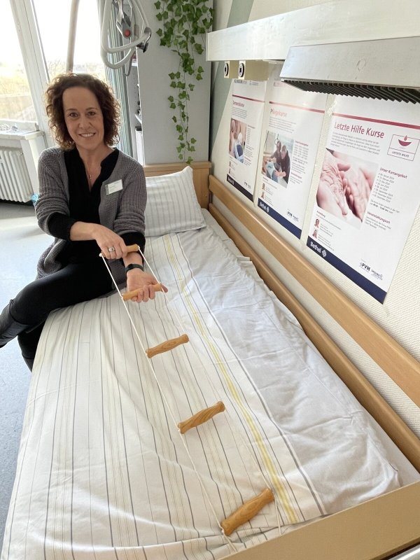 Pflegeexpertin Bianca Michler zeigt eine Bettleiter, die es Menschen ermöglicht, sich im Bett alleine aufzurichten. - © Carolin Nieder-Entgelmeier