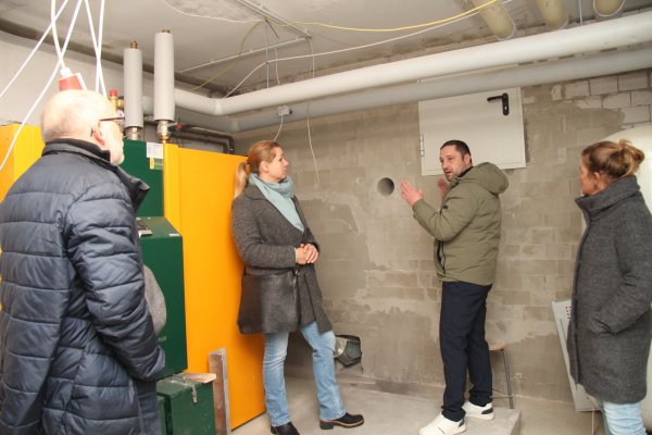 SPD-Politiker Manfred Rehse (von links), Bauamtsleiterin Ewa Hermann, Bauleiter Nikolai Stoll und Schulleiterin Irina Müller stehen im Heizungsraum. Hinter der Wand befindet sich das Holzpellet-Lager. - © Nadine Uphoff