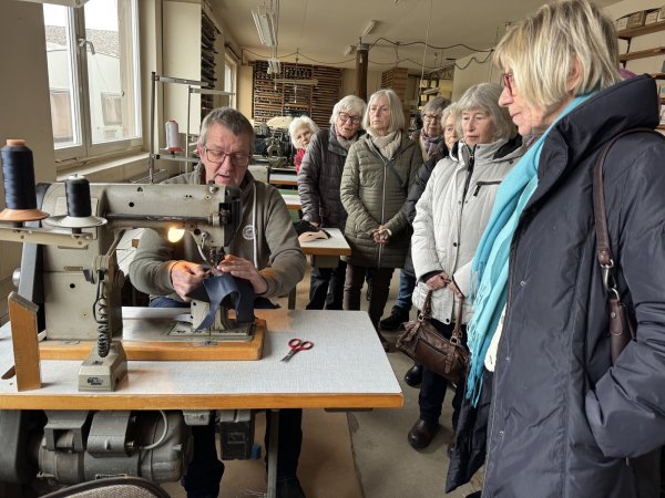 Klaus Süllwald demonstrierte in seinem Museum die Schritte der Schuhherstellung an der Nähmaschine, während die Damen-Boule-Gruppe aus Wülfer-Bexten gespannt zuschaut. - © Sandra Castrup