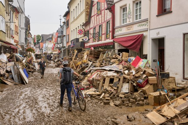 In Ahrweiler in Rheinland-Pfalz schiebt eine Frau ihr Fahrrad durch den Schlamm. Anwohner und Ladeninhaber versuchen, ihre Häuser vom Dreck zu befreien und unbrauchbares Mobiliar nach draußen zu bringen. - © Thomas Frey/dpa