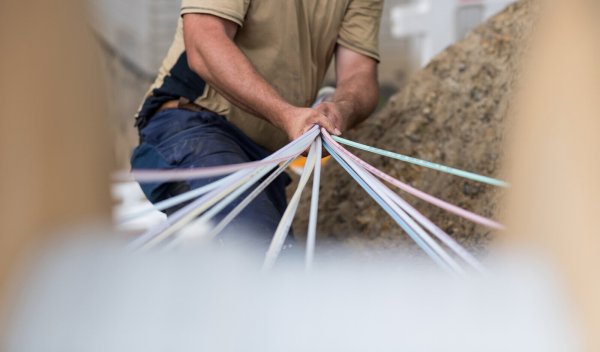 Ein Techniker verlegt Glasfaserkabel in einem Wohngebiet – eine Investition in die Zukunft des schnellen Internets. - © picture alliance/dpa