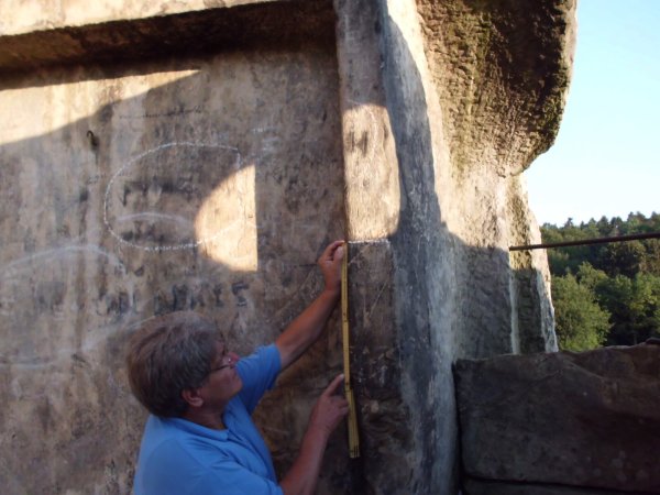 Ralf Koneckis-Bienas dokumentiert den Abstand der waagrechten Lichtschranke der Sonne am 9. August 2022 gegen 6.02 Uhr in der Höhenkammer von Felsen II zum unteren Steingesicht. - © Foto: Dirk Müller