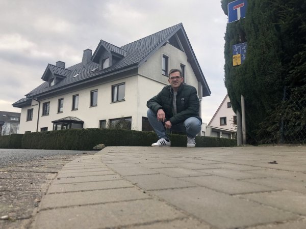 André Schielmann kniet an einem abgesenkten Bordstein am Sperlingsweg, für den er sich eingesetzt hatte. - © Sven Kienscherf