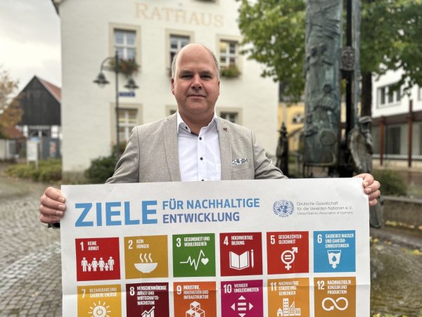 Bürgermeister Marcus Püster zeigt die 17 Entwicklungsziele, die der Erarbeitung der Nachhaltigkeitsstrategie zugrunde liegen. - © Gemeinde Schlangen