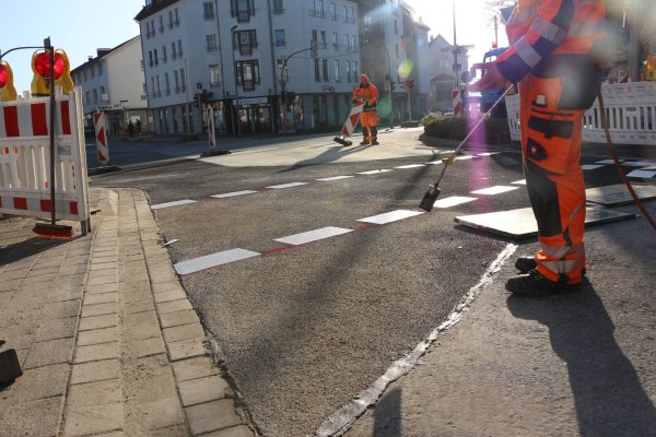 Arbeiter sind am Montagmittag dabei, der Straße den letzten Schliff zu verpassen. - © Janet König