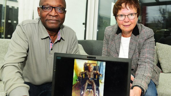Dorothea Ruhe, Vorsitzende des Kirchenvorstands in der Gemeinde St. Marien, und Denis Defo, Vorsitzender des Vereins Heart for Cameroon, zeigen stolz BIlder von Ali Abas in seinem Elektrorollstuhl. - © Nicole Ellerbrake