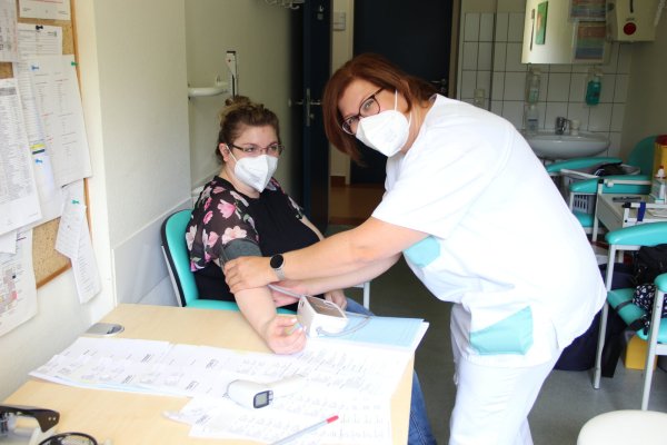 Stephanie Wilk ist mit Freude bei der Arbeit. Auch das Fieber- und Blutdruckmessen gehört zu ihren Aufgaben. Für das Foto hat sich Veronika Rudenski, kommissarische Pflegedienstleiterin, zur Verfügung gestellt. - © Agentur für Arbeit Detmold
