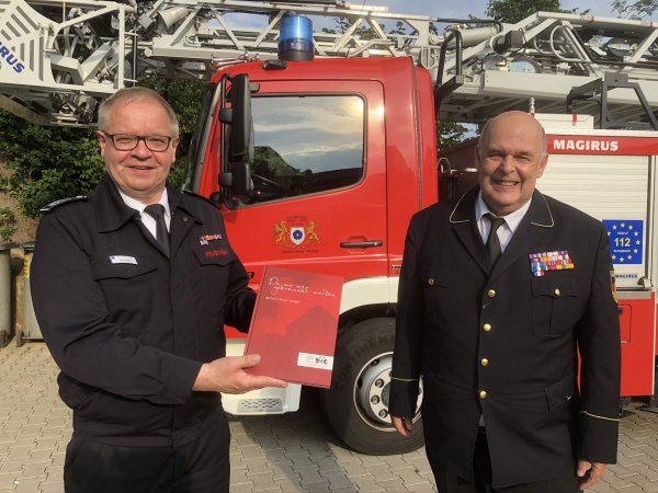 Stadtbrandinspektor Klaus Wegener (links) überreicht dem Leiter des Deutschen Feuerwehrmuseums, Rolf Schamberger, das erste Exemplar der Feuerwehr-Chronik. - © Till Brand