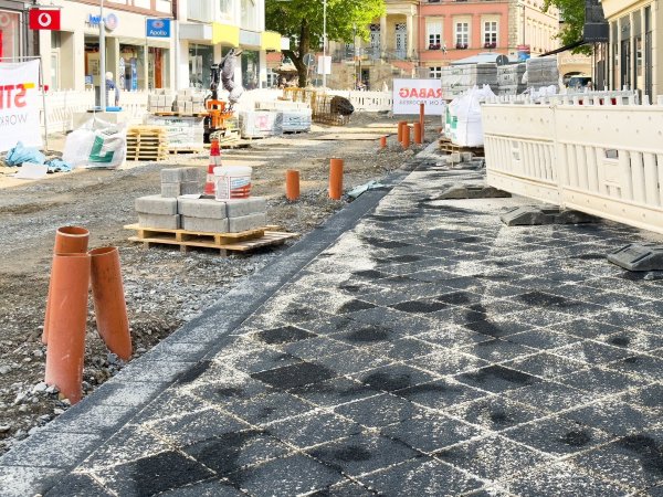 Die Pflasterarbeiten auf der Langen Straße haben begonnen. Noch sind die hellen Steine an vielen Stellen mit dem dunklen Füllmaterial übersät, das in die Fugen eingearbeitet wird. - © Raphael Bartling