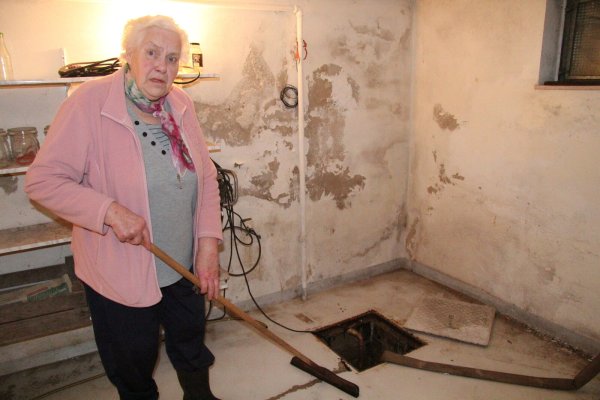 Inge Kronshage muss mehrmals täglich in den Keller gehen, um mit der Flitsche das Wasser in den Pumpensumpf zu schieben. Die Feuchtigkeitsschäden an der Wand sind unübersehbar. - © Dieter Asbrock