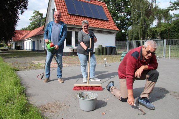 Eine lästige, aber notwendige Arbeit: Thomas Schneider (vorn), Bernhard Bentler und Angelika Schneider kratzen beim Arbeitseinsatz im Eggebad Unkraut aus den Fugen, stutzen Sträucher und halten den Kioskbereich in Schuss. - © Dieter Asbrock