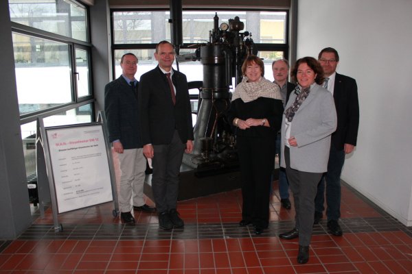 Prof. Dr.-Ing. Georg Heinrich Klepp, Prof. Dr. Jürgen Krahl, Hildegard Müller, Prof. Dr.-Ing. Thomas Schulte, Kerstin
Vieregge, MdB, und Prof. Dr. Stefan Witte (von links) versammeln sich fürs Foto vor Deutschlands ältestem betriebsfähigen Dieselmotor, der in der TH OWL ausgestellt ist. - © TH OWL