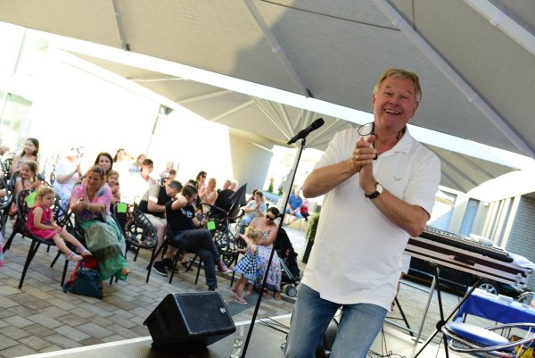 Trotz Sitzplätzen und Sicherheitsabstand lässt Kinderliedermacher Reinhard Horn schnell eine gute Stimmung im Innenhof des Rathauses entstehen. - © Nicole Ellerbrake