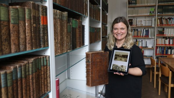 Sonja Beinlich mit einem alten Buch und einem modernen Tablet - sie leitet seit 1. April das Salzufler Stadtarchiv und hat viel vor. - © Alexandra Schaller