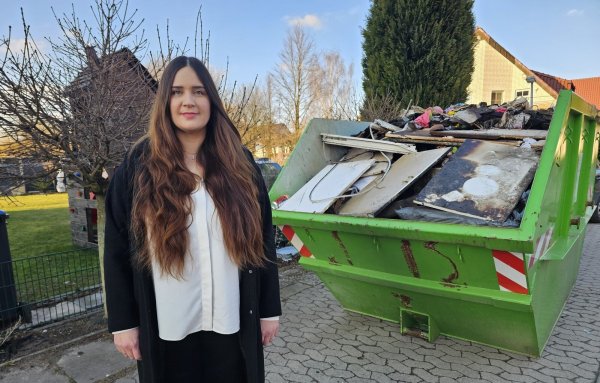 Susanne Semler hilft einer Familie, die bei einem Brand alles verloren hat. Das Haus im Sandkamp wird derzeit ausgeräumt, in der Mulde liegen die verbrannten und zerstörten Sachen. - © Astrid Sewing