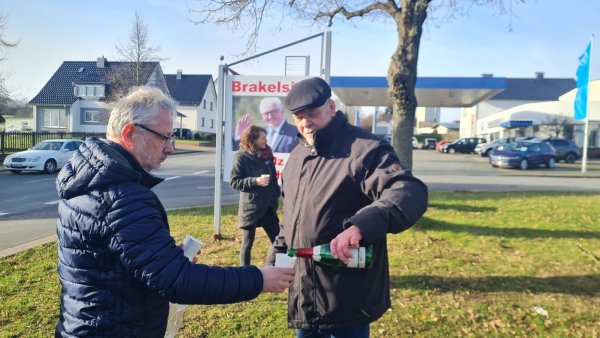 Ein Sektschlückchen zu Ehren des alten und neuen Bundespräsidenten: Dietmar Köller schenkt Uwe von Glembotzki ein. Im Hintergrund Dr. Inga Kretschzmar vor dem Plakat, das die Dorfgemeinschaft gestern nach der Wahl aufgestellt hat: "Brakelsiek ist stolz auf Dich!" - © Marianne Schwarzer(LZ)