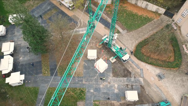 Mit einem Autokran werden die Weihnachtsmarkt-Hütten auf dem Schloßplatz an ihren Platz gehoben. Außerdem sind auf den Flächen Schutzplatten ausgelegt worden. - © Stadt Detmold