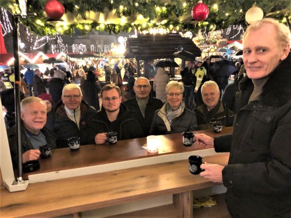 Lions-Präsident Joachim Markus schenkt am Glühwein-Stand auf dem Salzhof aus: Karl Brandes (von links), Helmut Becker (beide Kinderschutzbund), Jason Jochem (Courage-Initiative), Willi Terschluse (Lions) sowie Renate Nolte und Bernd Widmann (beide Initiative "MahlZeit") warten am Tresen. - © Thomas Reineke