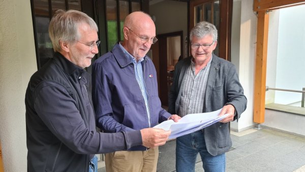 Die Initiatoren Udo Zippel (von links), Professor Dr. Rolf-Dieter Weege und Professor Dr. Hans-Jürgen Danneel blicken vor dem Dorfgemeinschaftshaus in Westorf in die ersten Unterschriftenlisten. - © Nadine Uphoff