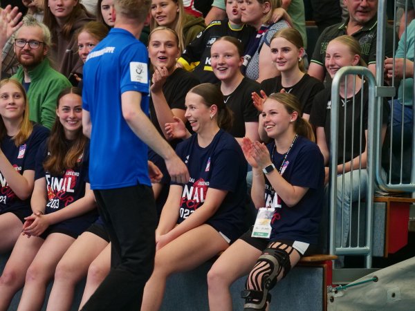 Mit einem Kreuzbandriss auf der Tribüne: Linksaußen Tessa Budelmann (vorne, rechts) schaut ihren Teamkameradinnen zu und spendet voller Zufriedenheit Applaus. - © Jörg Hagemann