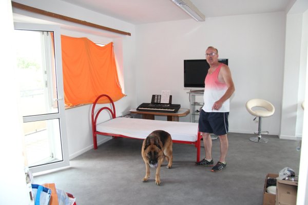 Franz Lozada (mit seinem Hund) hilft ehrenamtlich der ukrainischen Familie und zeigt das Wohnzimmer in der ansonsten geräumigen Dachgeschosswohnung. - © Cordula Gröne(LZ)