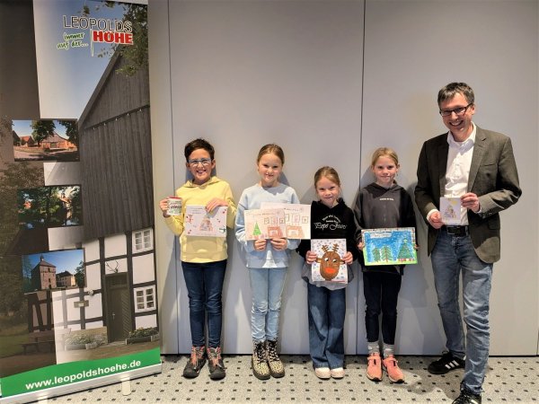 Gewinner Finn (links), die Zweitplatzierten Sofia, Hanna und Merith und Bürgermeister Martin Hoffmann mit der Weihnachtskarte. - © Grundschule Asemissen
