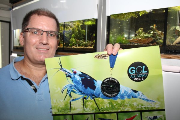 Markus Schultz mit seiner "Ocean Blue"-Garnele als Poster vor den Becken, in denen sich die kleinen Krabbler tummeln. - © Sandra Castrup