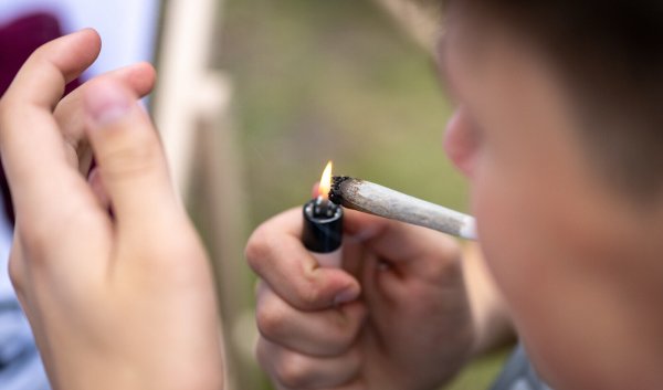 Ein junger Mann zündet sich einen Joint an – die Debatte um die Cannabis-Legalisierung in Deutschland spitzt sich wieder zu. - © picture alliance/dpa