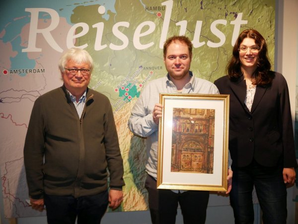 Ausstellung "Reiselust" mit Bild vom Tor des Hexenbürgermeisterhauses. Jürgen Scheffler, Museumsleiter Fabian Schörder und Dr. Mayarí Granados freuen sich über die Bilder von Monnickendam, die bis Ende des Jahres im Hexenbürgermeisterhaus zu sehen sind (von links). - © Thomas Krügler