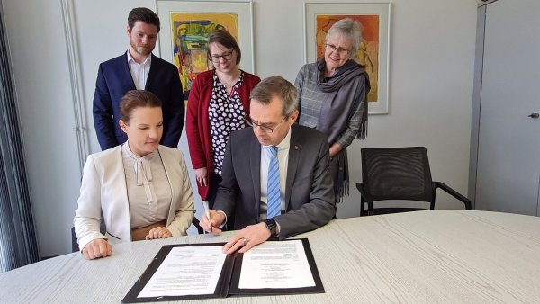 Kathleen Hendriks (Senior Director People & Culture, Phoenix Contact) und Jörg Bierwirth als Verbandsvorsteher der Volkshochschule Lippe-Ost unterzeichnen den neuen Kooperationsvertrag, während Arne Lütkehaus (Director Learning & Development, Phoenix Contact), Fachbereichsleiterin Nicole Grützmacher und Leiterin Andrea Lemm von der Volkshochschule (von links) zuschauen. - © Marianne Schwarzer