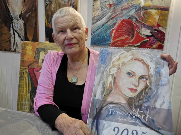 Sieglinde Strohmeier in ihrem Atelier mit eigenen Bildern und dem Frauen-Kalender 2025. - © Sylvia Frevert