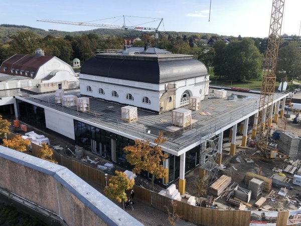 Das neue Kurhaus aus der Vogelperspektive: Das Dach des historischen Galasaals in der Mitte des Komplexes ist jetzt viel deutlicher zu sehen. Um den Saal herum befinden sich an drei Seiten die eingeschossigen, großzügig verglasten Arkaden, die künftig das Foyer mit Garderobe und Bistro, den Sanitärbereich, eine Küche zum Aufwärmen von Speisen sowie mehrere Tagungsräume für bis zu 600 Gästen beherbergen. - © Thomas Reineke