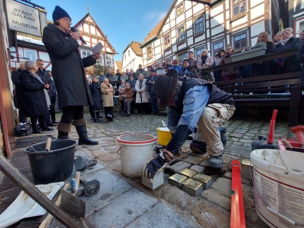 Während die Mitglieder der Vorbereitungsgruppe aus dem Leben der Familie Bachrach und des Lehrlings Willi Harf berichten, verlegt Künstler Gunter Demnig die Stolpersteine. - © Michaela Weiße