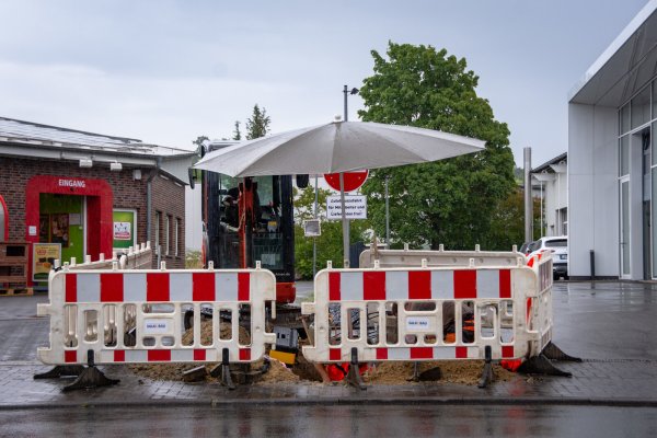 Bauarbeiter reparieren am Dienstag Schäden an einer Internet-Kupferleitung an der Klingenbergstraße. Den wiederkehrenden Regenschauern trotzen sie mit einem Sonnenschirm über der Grabungsstelle. - © Raphael Bartling
