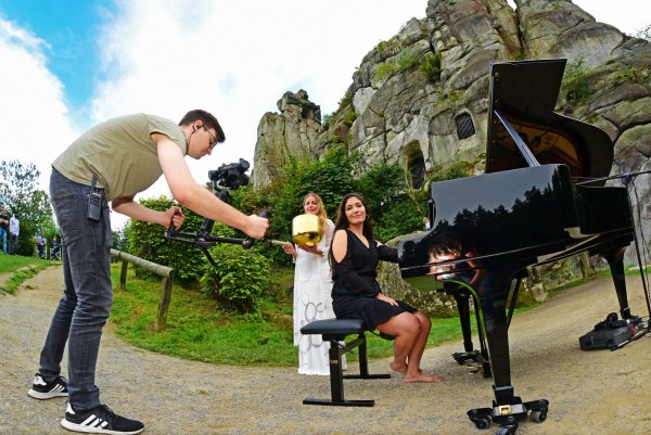 Kameramann Jonas Jakob filmt Pianistin Constanza Ibarra und Mirja Lang (Gesang und Klangschale) bei einem außergewöhnlichen Konzert an den Externsteinen. - © Nicole Ellerbrake