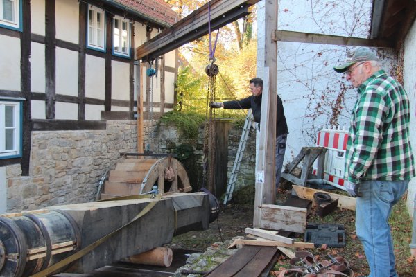 Lars Kine (links) und Dieter Knaup bugsieren die Antriebswelle vom Anhänger vor das neue Mühlrad. - © Nadine Uphoff