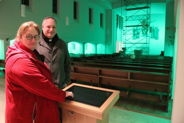 Die Lichterkirche ist startbereit: Pfarrgemeinderatsvorsitzende Christiane Berghahn und Pfarrer Stefan Schiller stehen am Bedienpult, an dem Besucher verschiedene Programme mit Lichtstimmungen, Kirchenliedern und Andachten abrufen können. Die schlichte Neugestaltung lässt die Farben besonders gut zur Geltung kommen. - © Dieter Asbrock