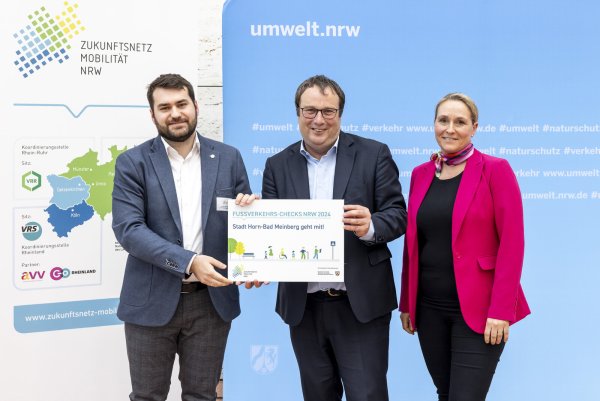 Klimaschutzmanager Lorenz Weimer (links) hat die Teilnahmeurkunde zum Fußverkehrs-Check von NRW-Umwelt- und Verkehrsminister Oliver Krischer und NWL-Leiterin Daniela Niestroy entgegen genommen. - © Smilla Dankert