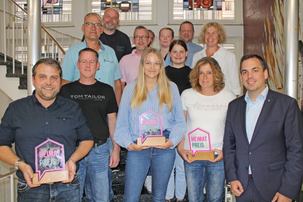 Bürgermeister Torben Blome (rechts) und die weiteren Jury-Mitglieder überreichen die Trophäen für den Heimatpreis. Ronny Engel mit Thomas Hagedorn (vorne von links, SV Niese), Gillian König (IQ Lügde – SOS Kinderdorf) und Susanne Müller (Dorfgemeinschaft Rischenau) nehmen sie stellvertretend entgegen. - © Nico Düllmann