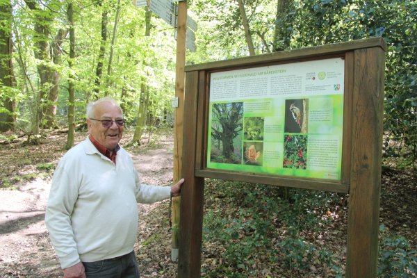 Adolf Nagel steht an einer Infotafel zum Bärenstein, der auch auf der Strecke der Blaubeer-Route liegt. - © Dieter Asbrock