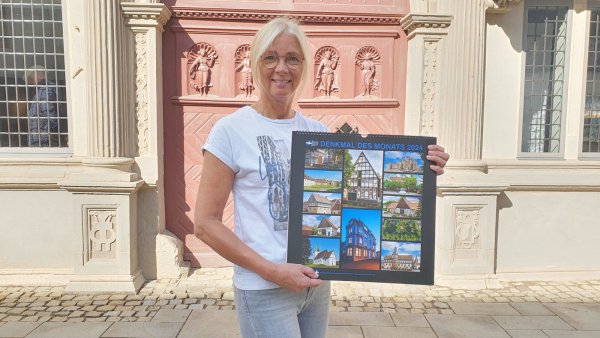 Sandra Sasse, Mitarbeiterin der Geschäftsstelle der Arbeitsgemeinschaft Historische Stadt- und Ortskerne NRW, präsentiert den Denkmal-Kalender für 2024. - © Alte Hansestadt Lemgo