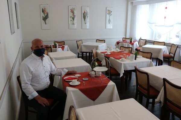 Michael Sasse, Inhaber des Kurpark-Hauses und Vorsitzender des Salzufler Vereins "Kur- und Touristik", sitzt in seinem Frühstücksraum. Damit die Abstandsregeln gewahrt werden, werden nicht alle Tische eingedeckt, statt Buffet gibt es Etagères am Tisch. - © Alexandra Schaller