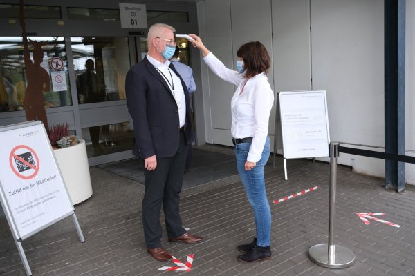 Die Leiterin des Klinikservice, Birgit Kelle, misst beim Pressesprecher Christian Ritterbach die Körpertemperatur mit einem Infrarot-Thermometer. - © Klinikum Lippe