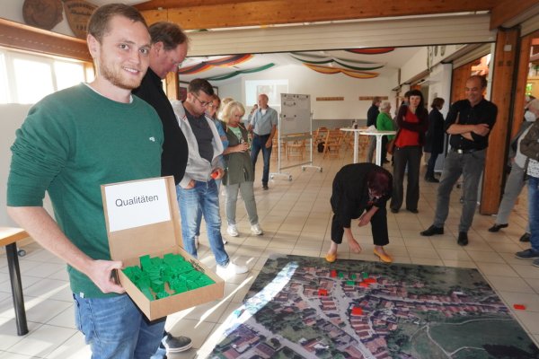 Die Bürger markieren die Stärken und Schwächen Schwalenbergs auf einem Luftbild mit farbigen Legosteinen. Til Reher (links), Mitarbeiter des Planungsbüros, steht ihnen zur Seite. - © Michaela Weiße