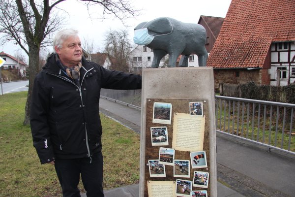 Für den neuen Ortsbürgermeister von Elbrinxen, Wolfgang Siefert, ist das Denkmal, das an die Schweinerennen in den 80ern erinnert, Synonym für eine starke Dorfgemeinschaft. Auch das Schwein trägt in der Corona-Pandemie Maske, das ist klar. - © Silke Buhrmester(LZ)